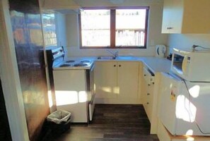 Une cuisine de taille réduite équipée d’une cuisinière, d’un évier et d’un four à micro-ondes.