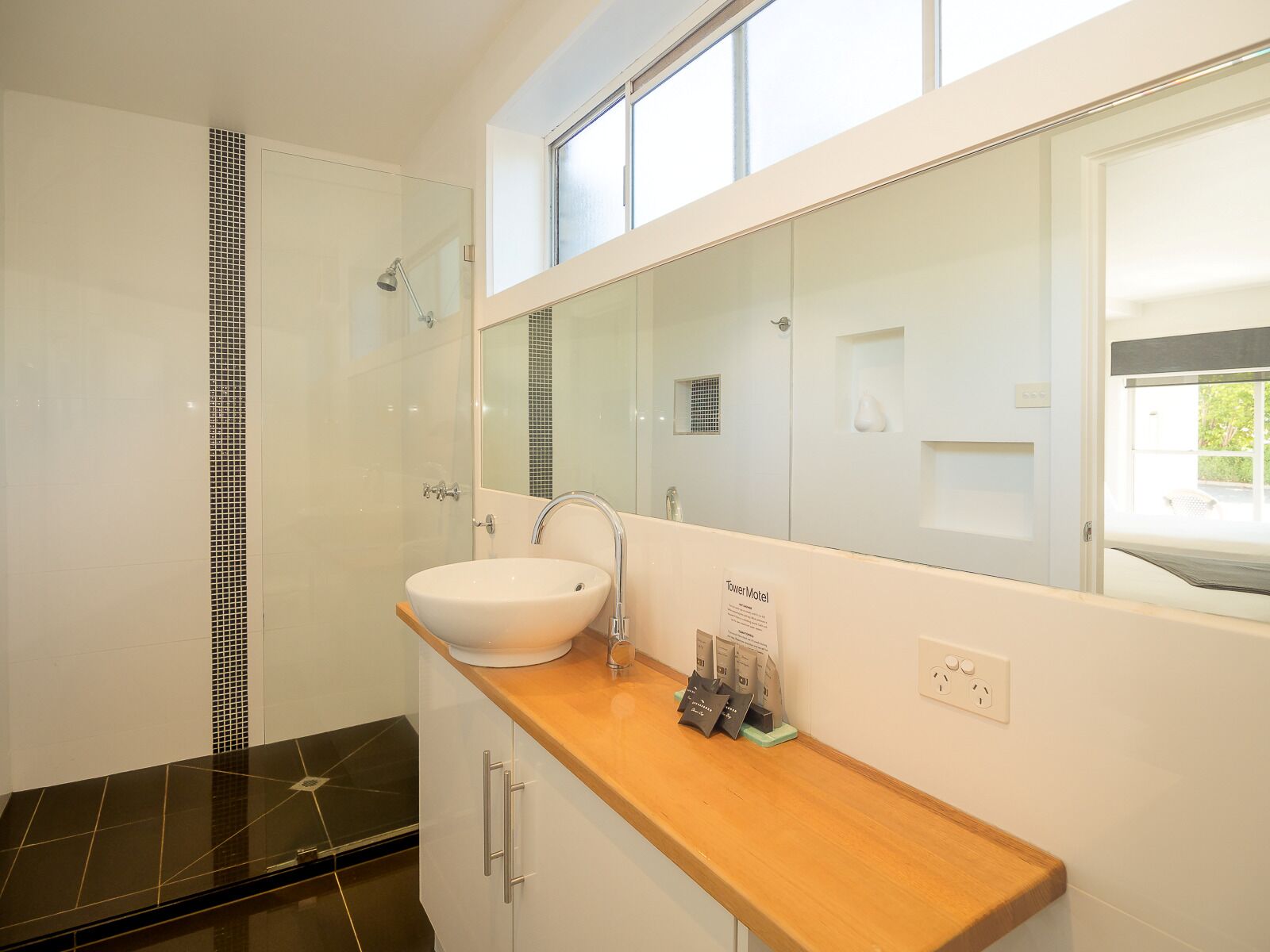 A modern bathroom with a large mirror, a sink, and a shower.