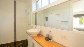 A modern bathroom with a large mirror, a sink, and a shower.
