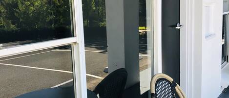 A room with a round table and two chairs, a door with the number 7, and a view of a parking lot and trees outside.