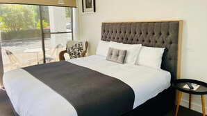 A hotel room with a large bed, a view through a sliding door, a small table, and a chair. - Tower Motel (Marysville)