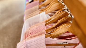 A clothing rack with various garments, including a pink dress with a name tag.