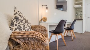 A modern room with a desk, two chairs, a TV, and a wicker chair. - Tower Motel (Marysville)