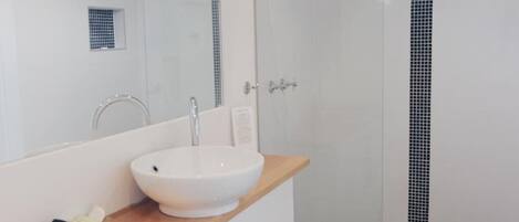 Un baño con un lavamanos blanco, una encimera de madera y un espejo encima.