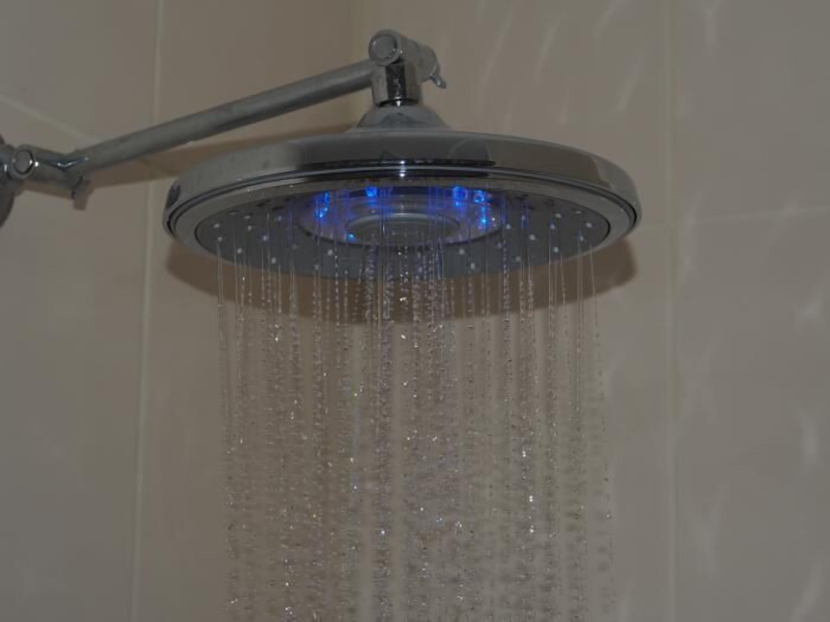 Un cabezal de ducha con múltiples boquillas y un flujo de agua visible.