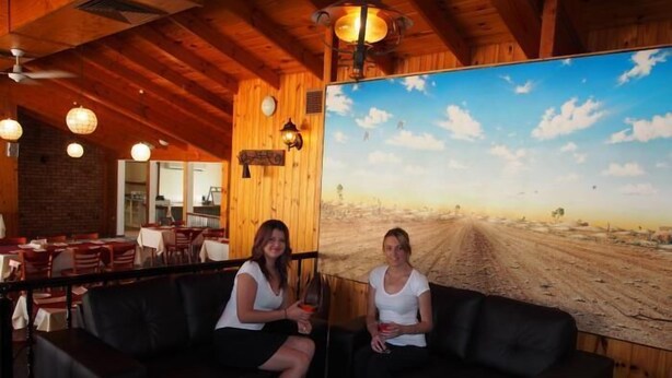 A rustic interior with wooden walls and a large painting of a desert landscape.