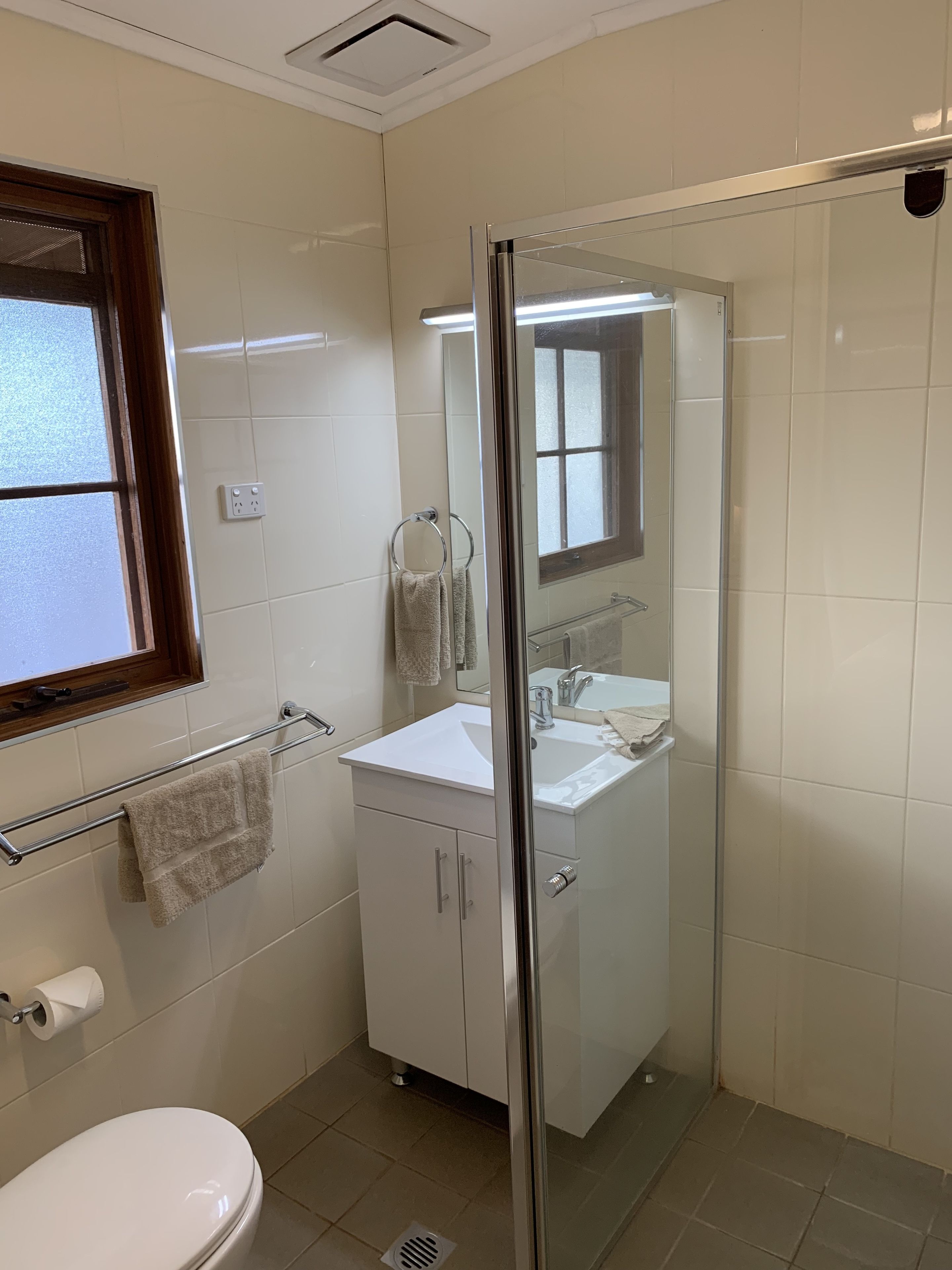 Un baño moderno con cabina de ducha de vidrio, un lavamanos blanco y un inodoro.
