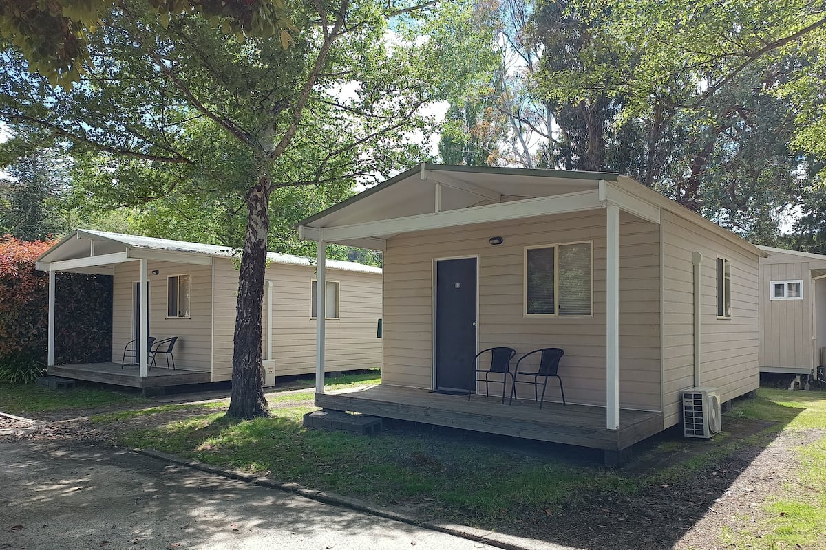 A row of mobile homes with a covered porch and two chairs.