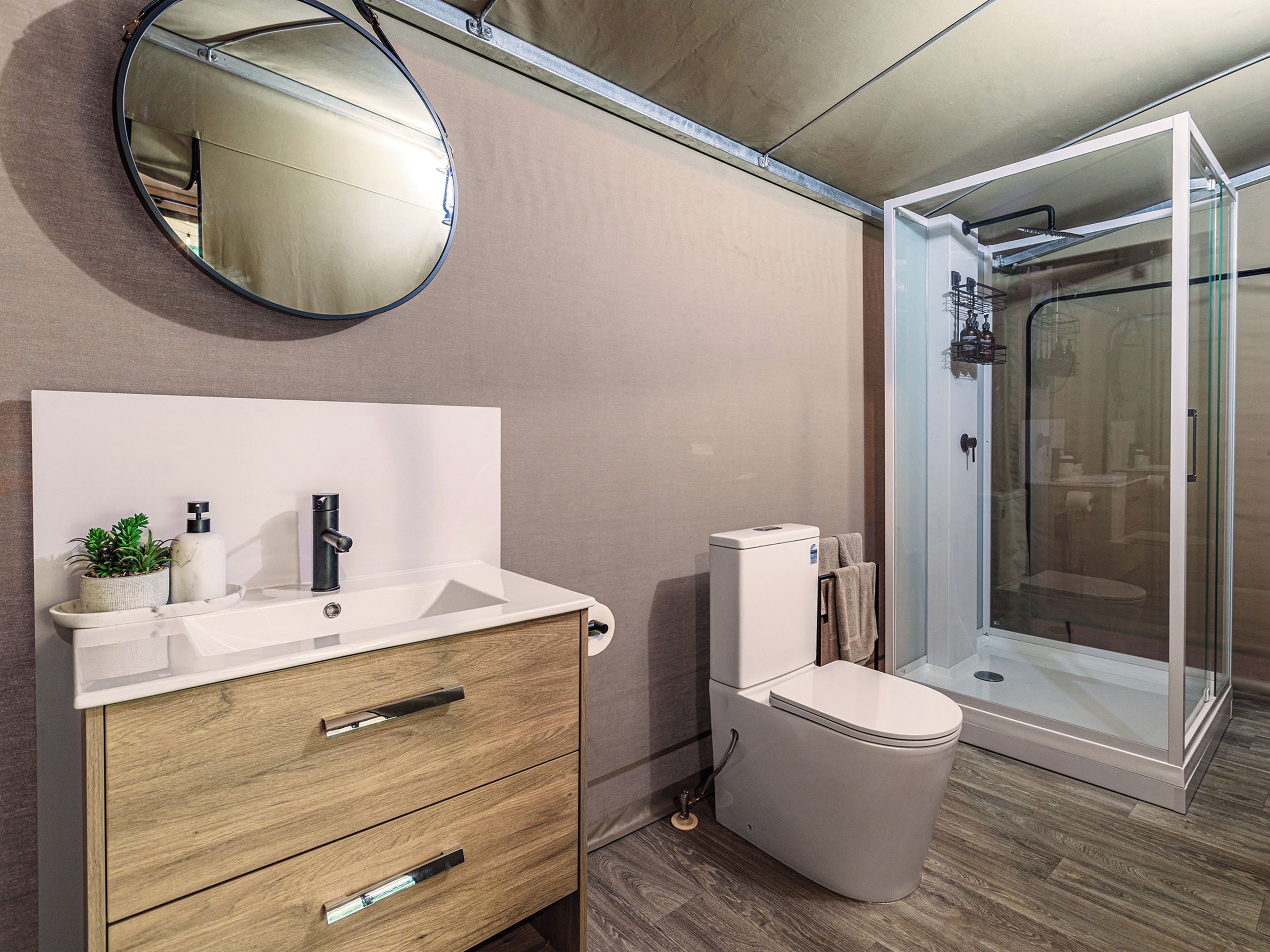 Un baño moderno con tocador de madera, inodoro, cabina de ducha y espejo.