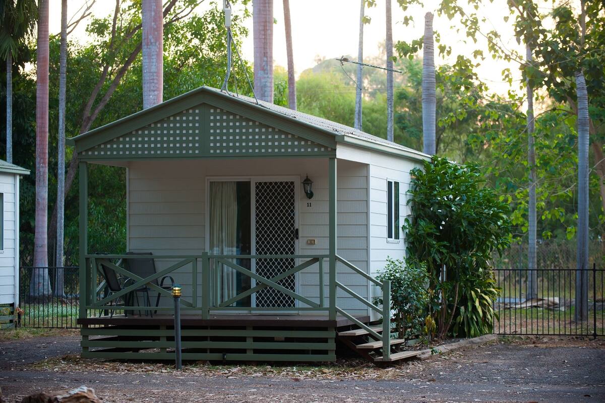 Eine kleine, eingeschossige Hütte mit Veranda, einer Tür und einem Fenster.