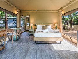 Un dormitorio amplio con una cama grande, mesitas de noche, un escritorio y sillas.