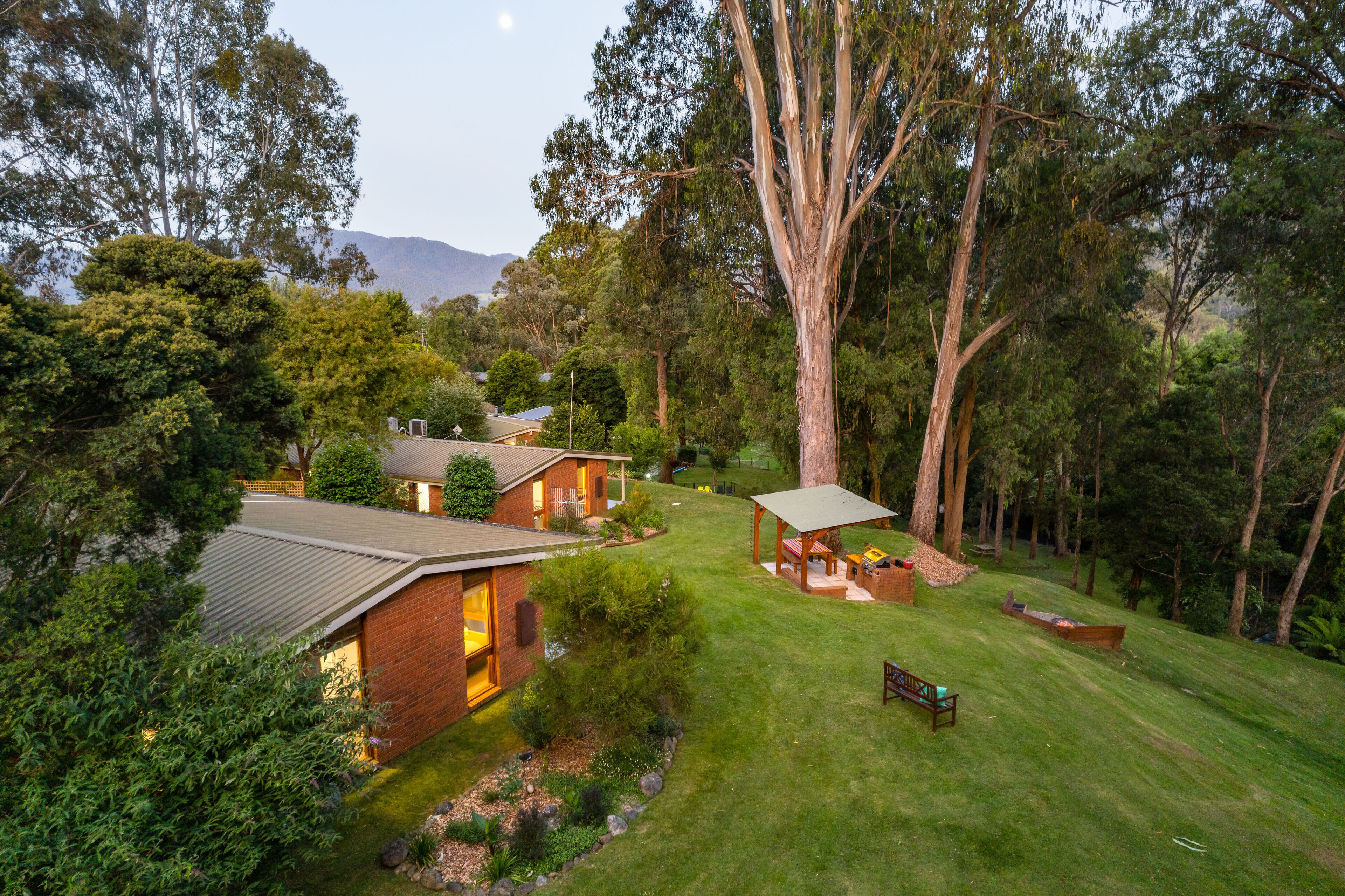 A house with a brick exterior, a covered patio, and a lawn.