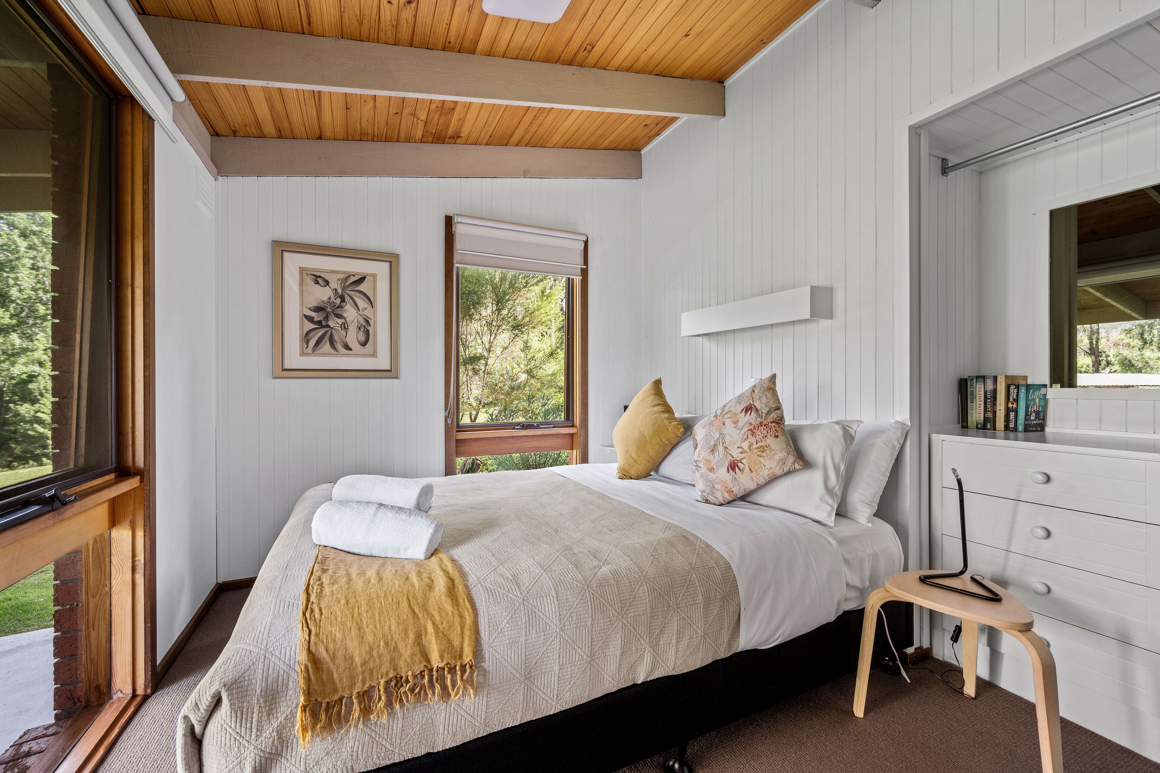 A bedroom with a bed, a window, a bedside table, and a dresser.