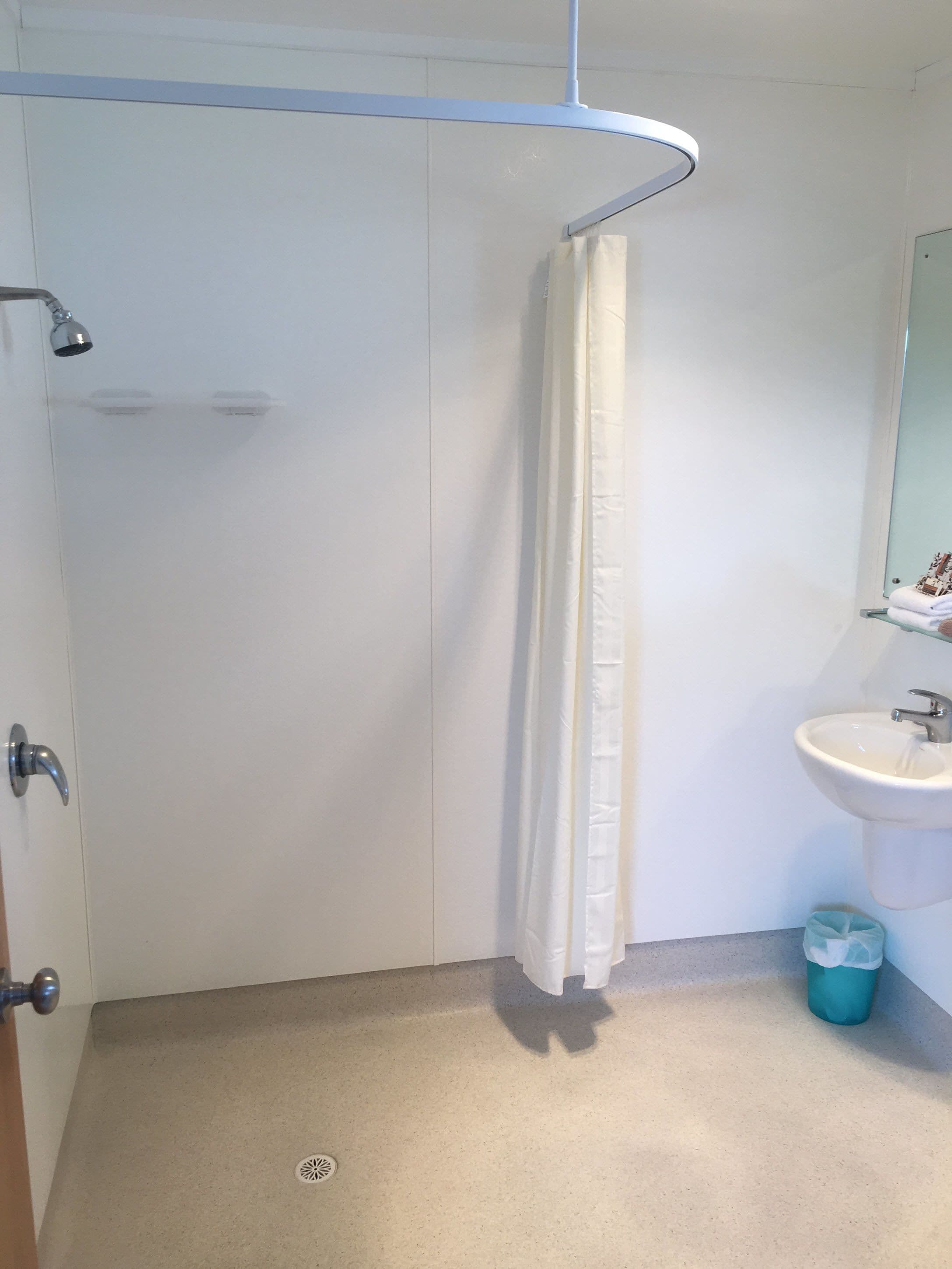 Une salle de bain avec une douche, un lavabo et un miroir.