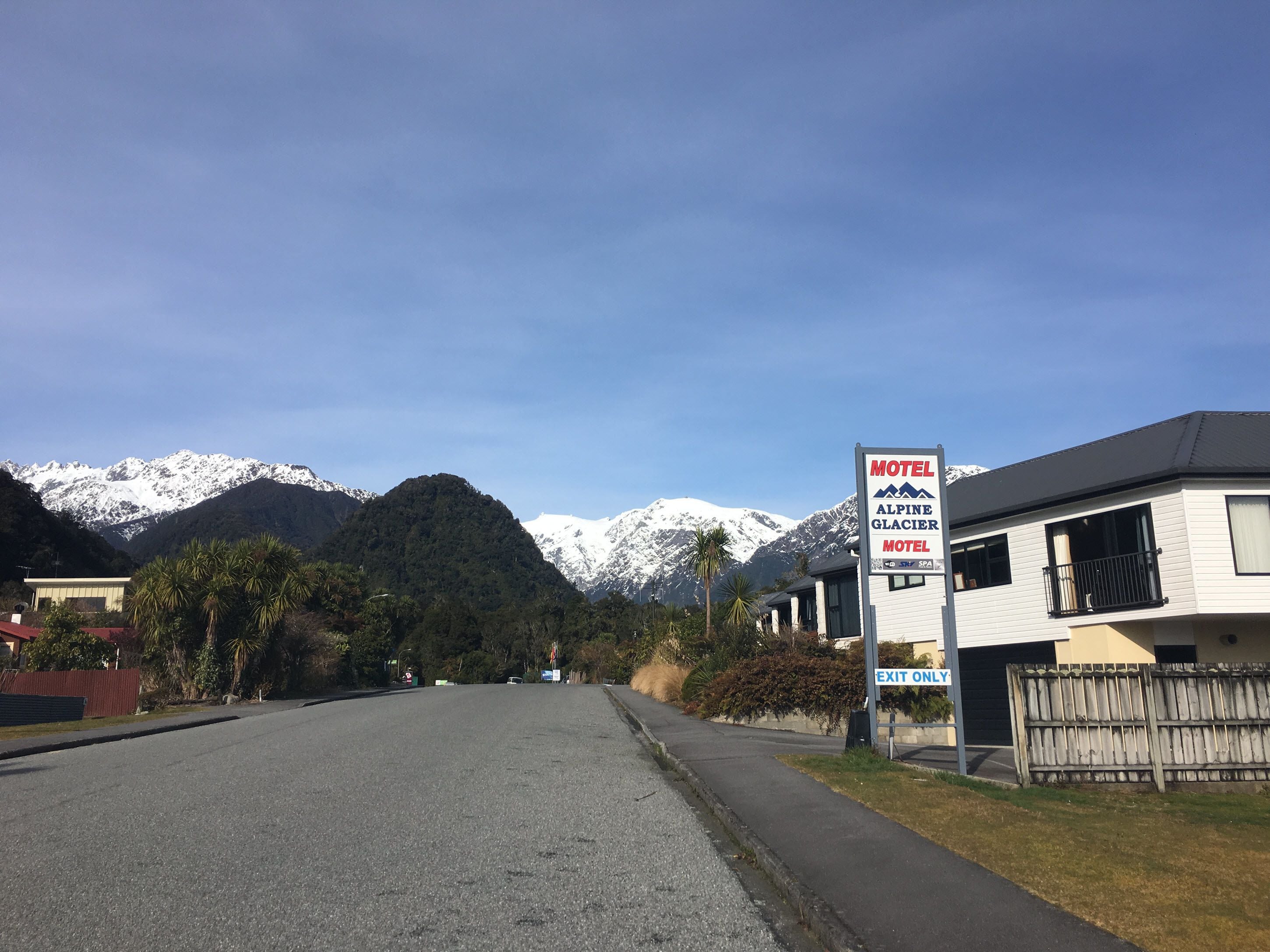 Vista de la calle con un cartel del Motel Glaciar Alpino, con una montaña al fondo.