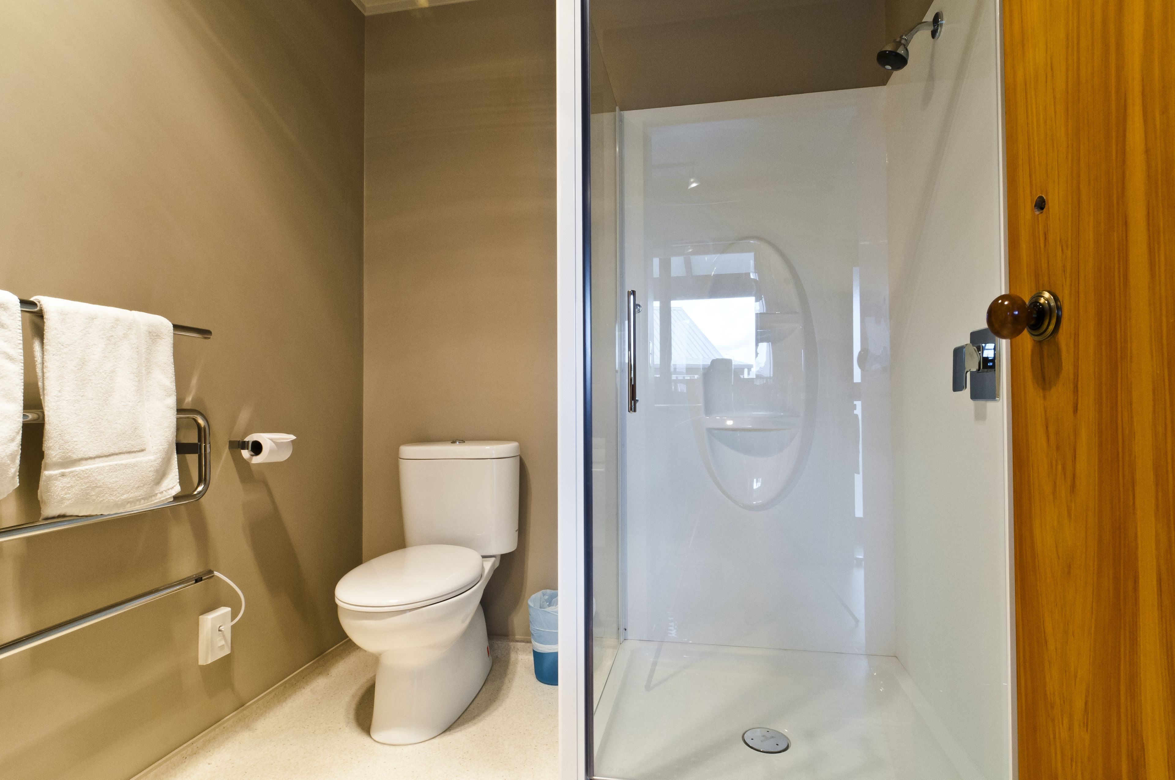 Un bagno con il water, una cabina doccia in vetro e un portascopevoli.