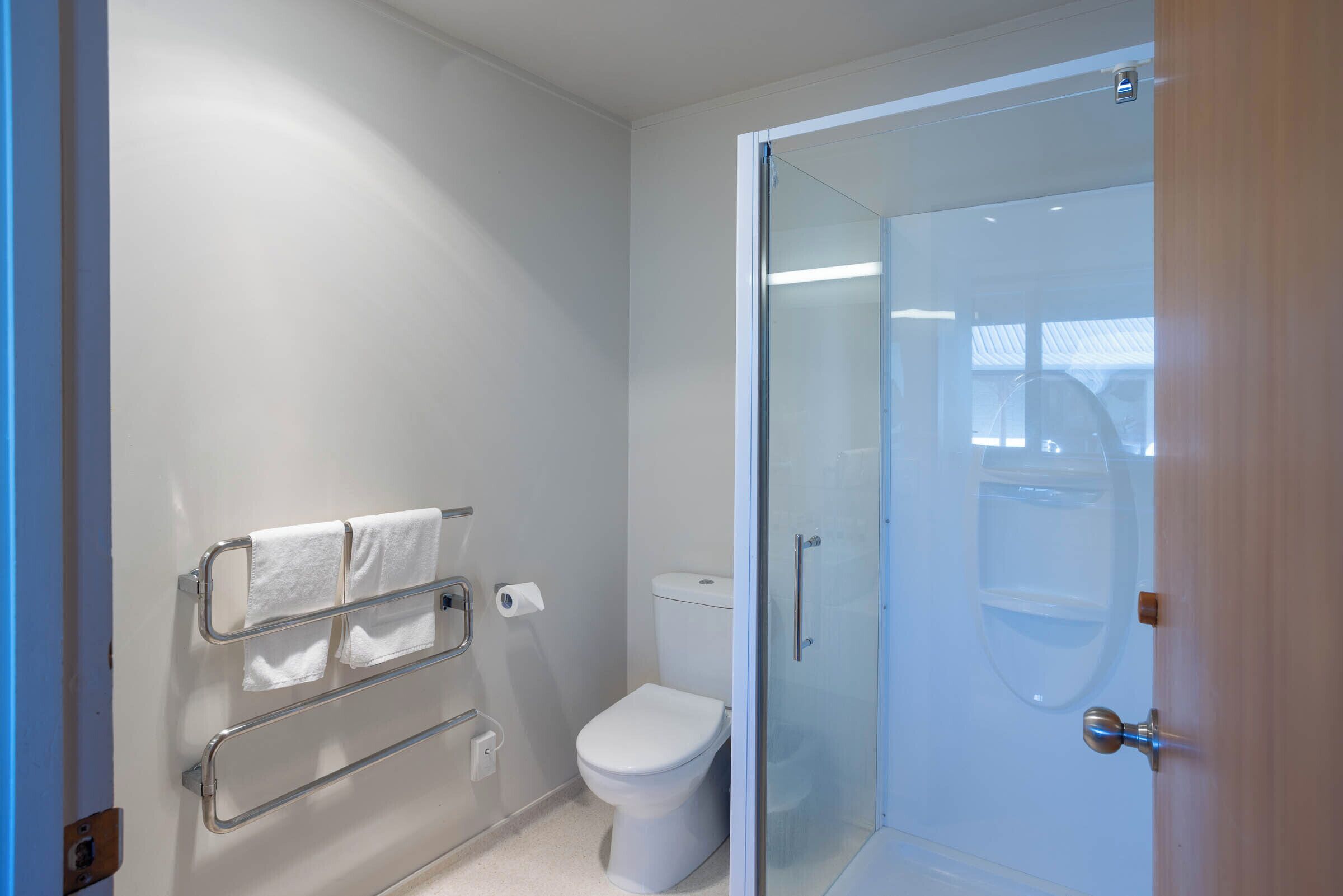 Un bagno moderno con cabina doccia in vetro, un water e un porta asciugamani.