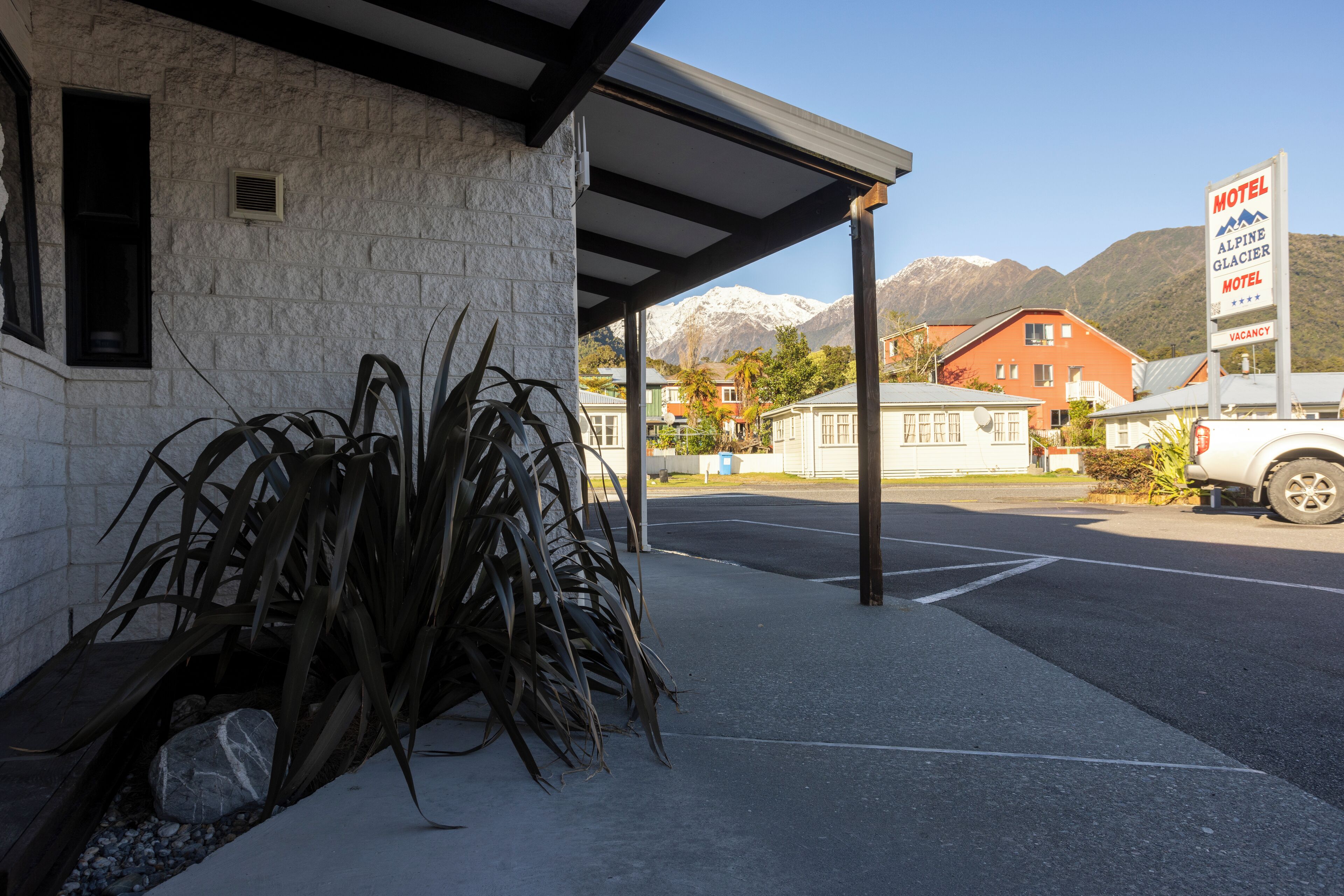 Un motel avec une façade en pierre, un parking couvert et un panneau indiquant qu’il y a des chambres disponibles.