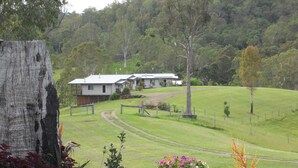 A rural landscape with a house, a dirt path, and a grassy field. - Yabbaloumba Retreat (Cambroon)
