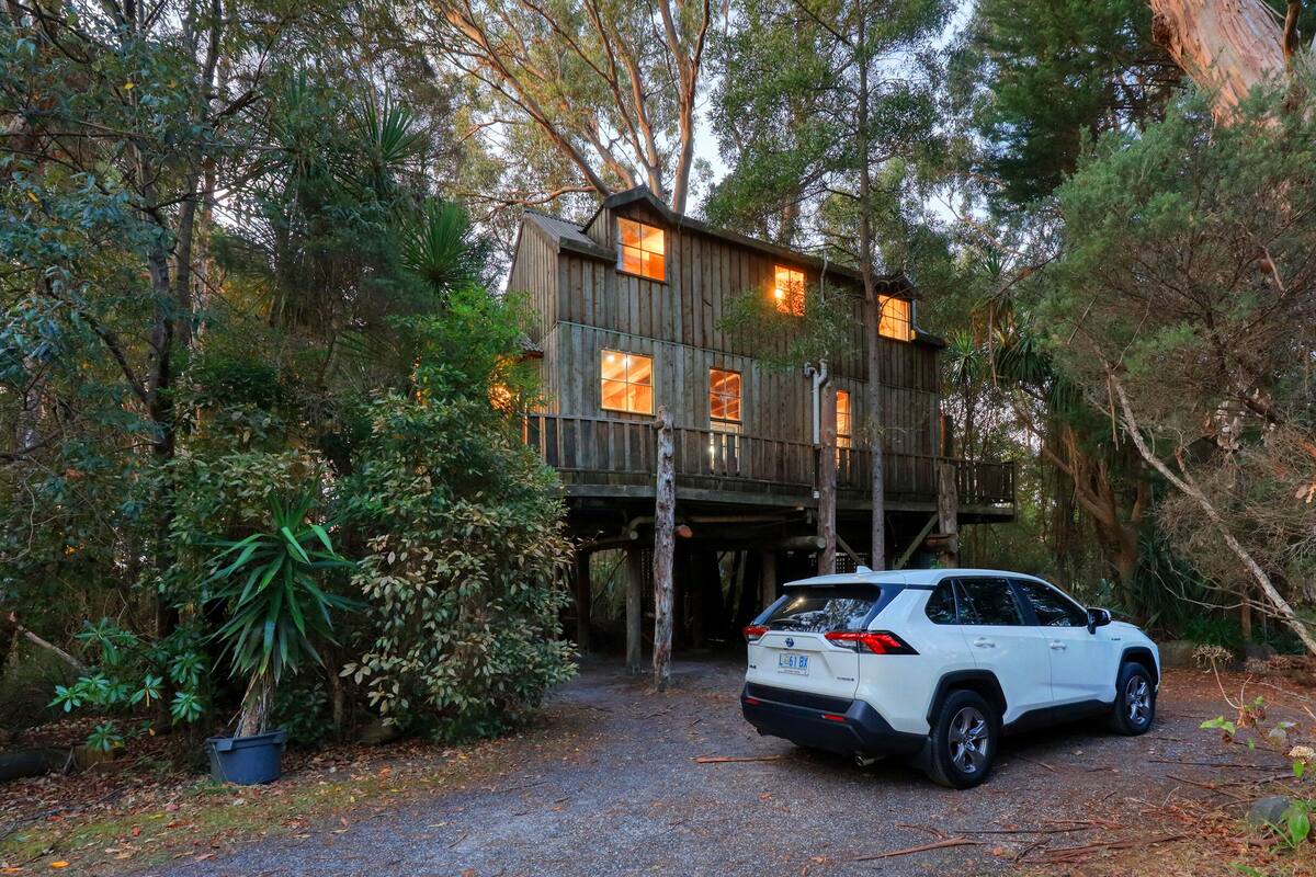 Une cabane en bois avec une voiture garée devant.