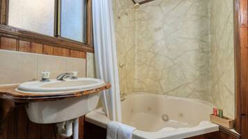 A bathroom with a wooden vanity, a sink, and a bathtub.
