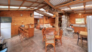 L’intérieur d’un chalet rustique, avec un coin repas en bois, des éléments décoratifs en pierre et une cuisine dotée d’un mur en pierre.