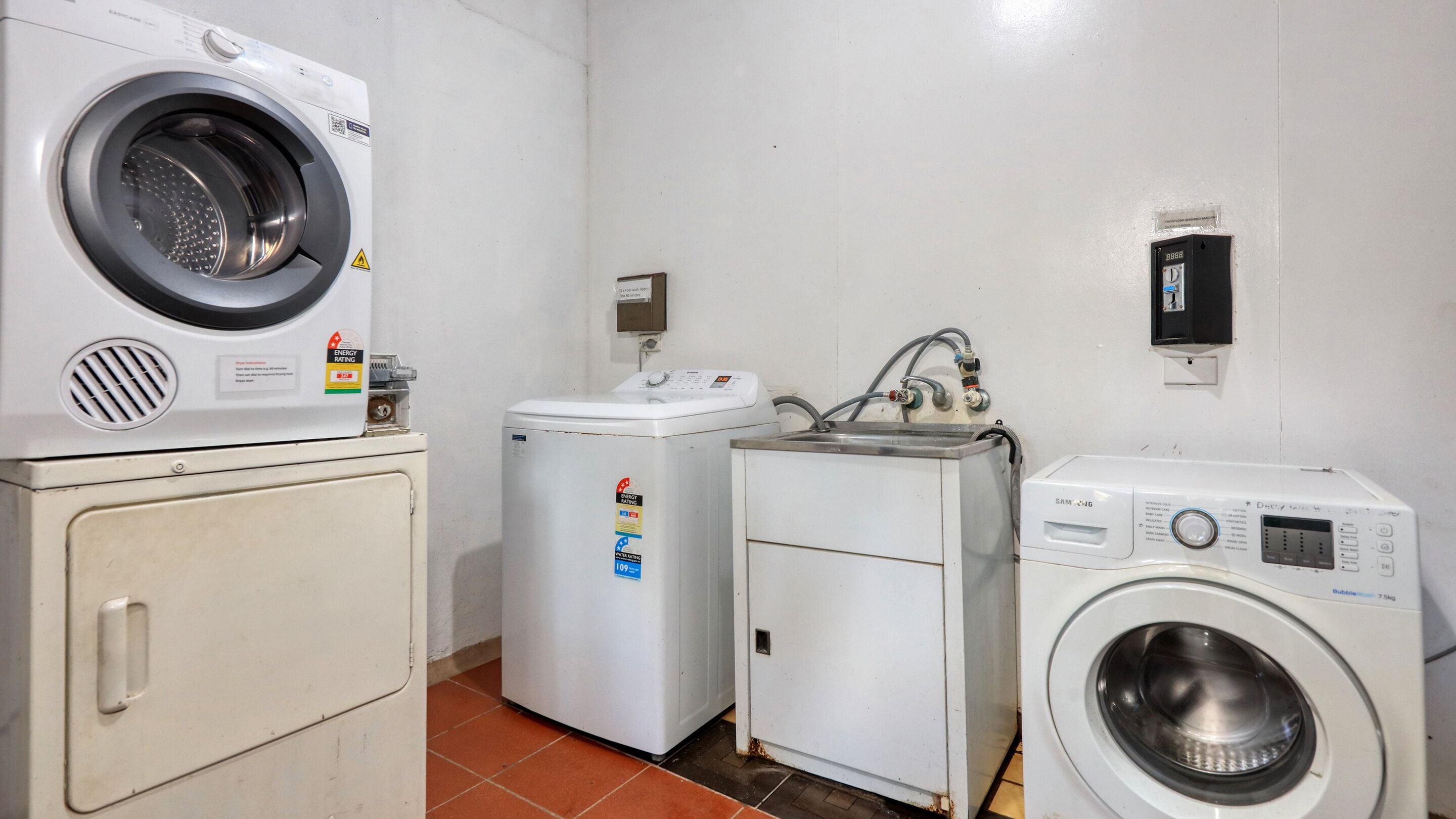 A laundry room with a front-loading washer, a top-loading dryer, and a compact washing machine.