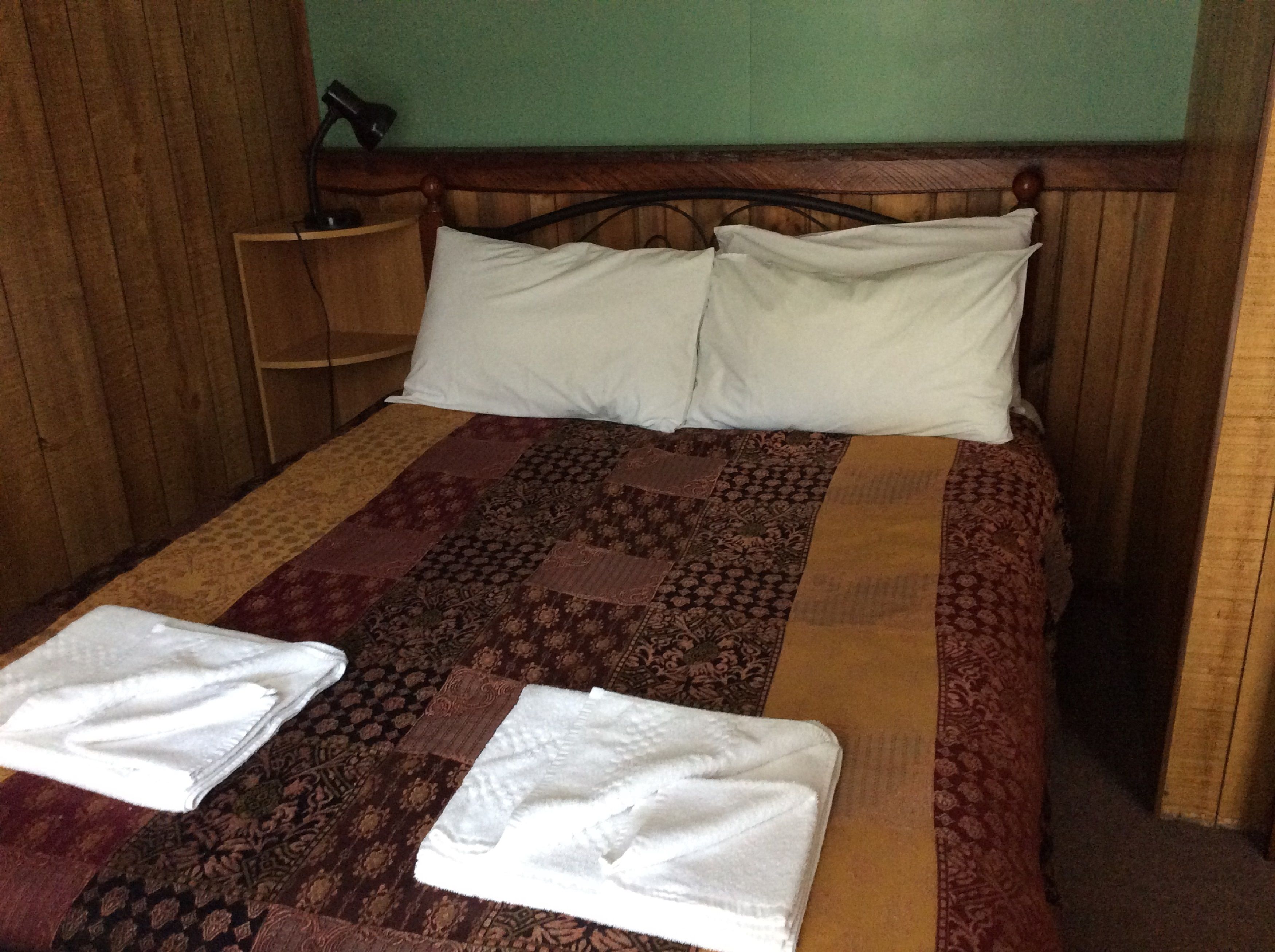 Una cama con una colcha estampada, dos almohadas y dos toallas dobladas.