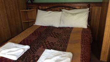 Una cama con una colcha estampada, dos almohadas y dos toallas dobladas.