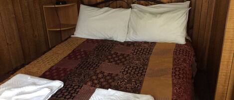 Una cama con una colcha estampada, dos almohadas y dos toallas dobladas.