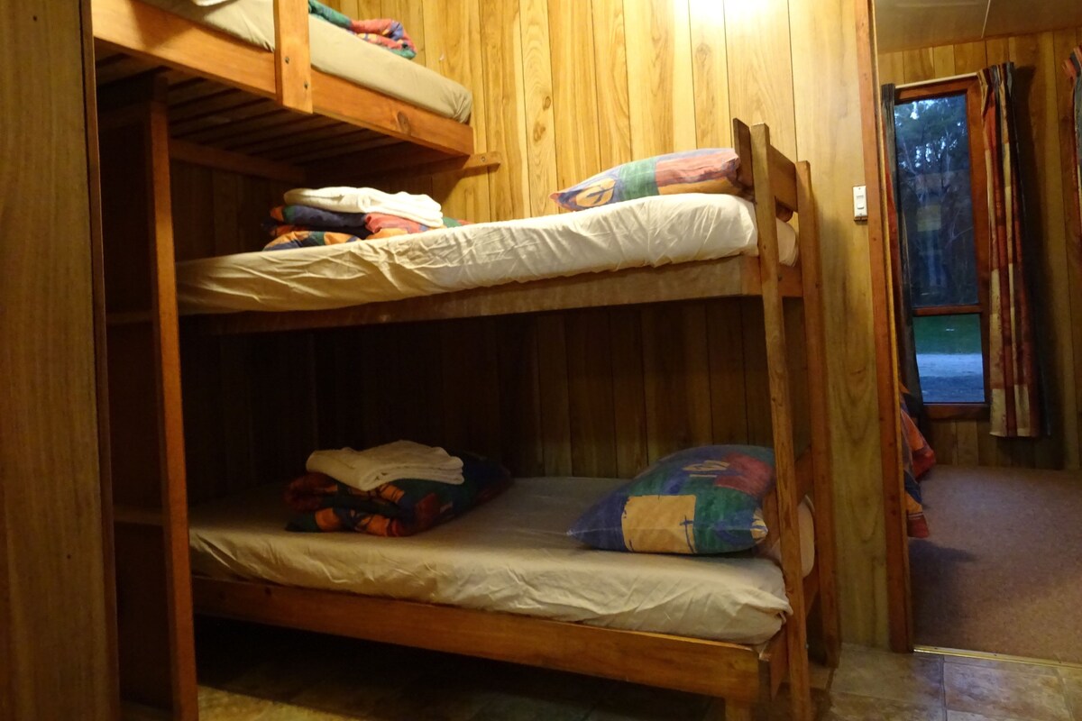 Habitación con literas, paredes de madera y una ventana.