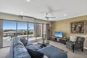 Una sala de estar moderna con un sofá grande, una mesa de centro, un televisor y un sillón estampado.
