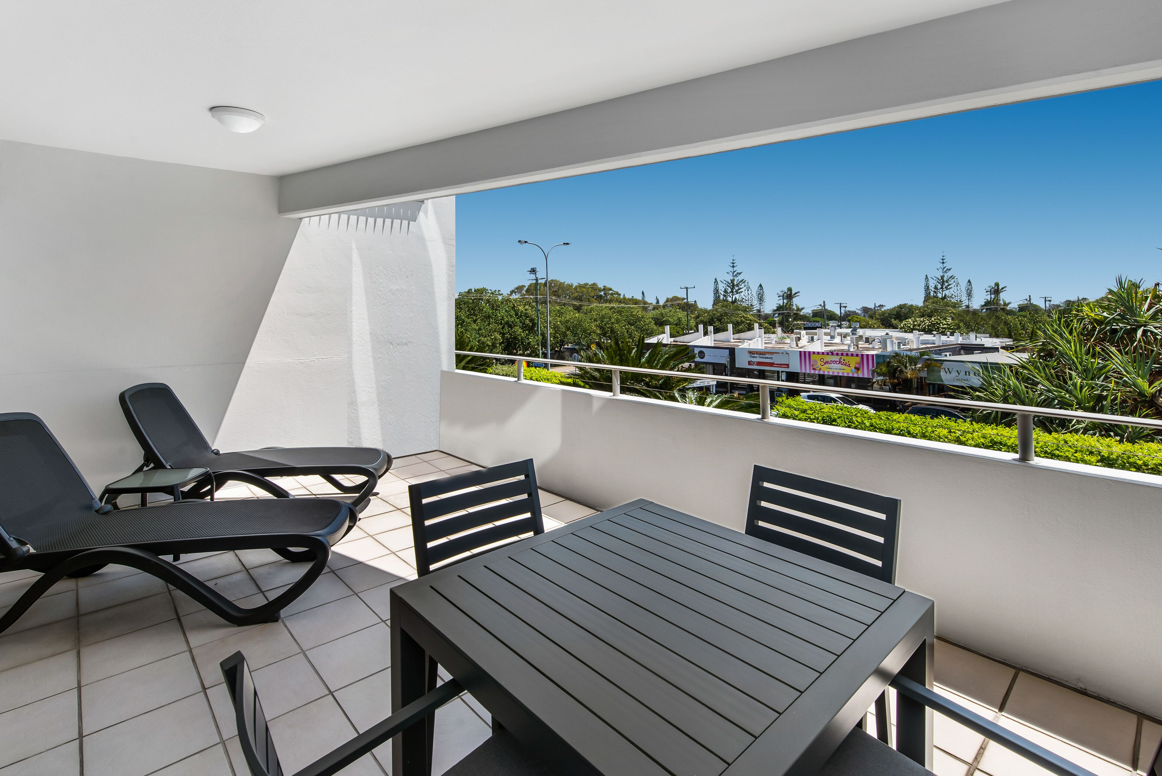 Een balkon met een tafel en stoelen, een uitzicht op een stadsbeeld en een heldere lucht.