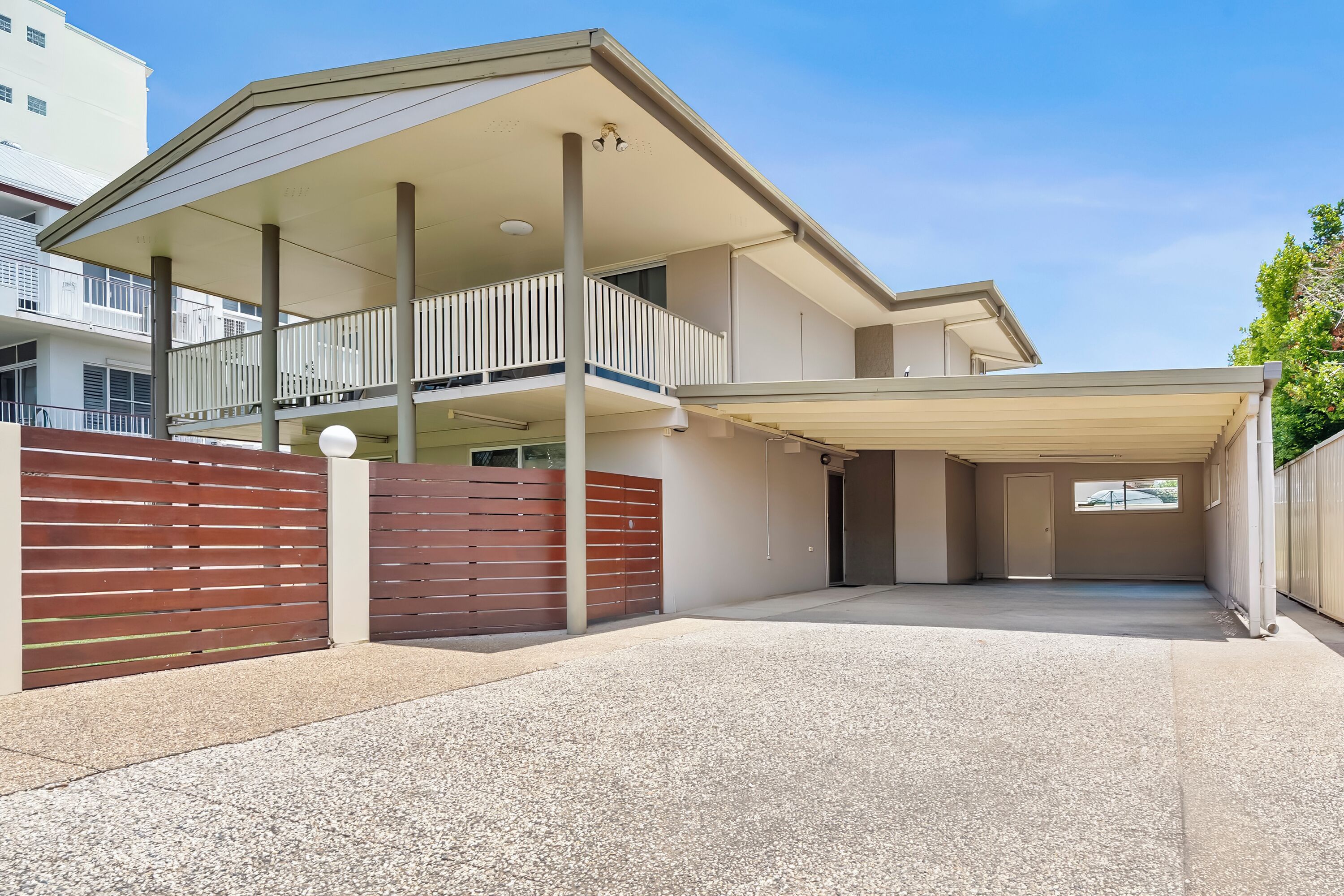 A two-story building with a covered outdoor area, a gated entrance, and a visible balcony.