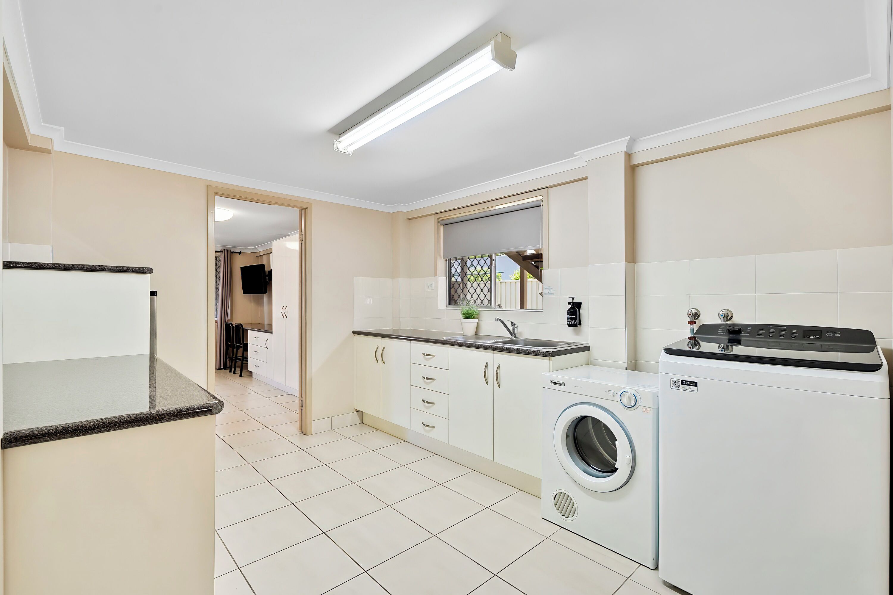 A modern kitchen with a washing machine, a built-in oven, and a flat-screen TV.