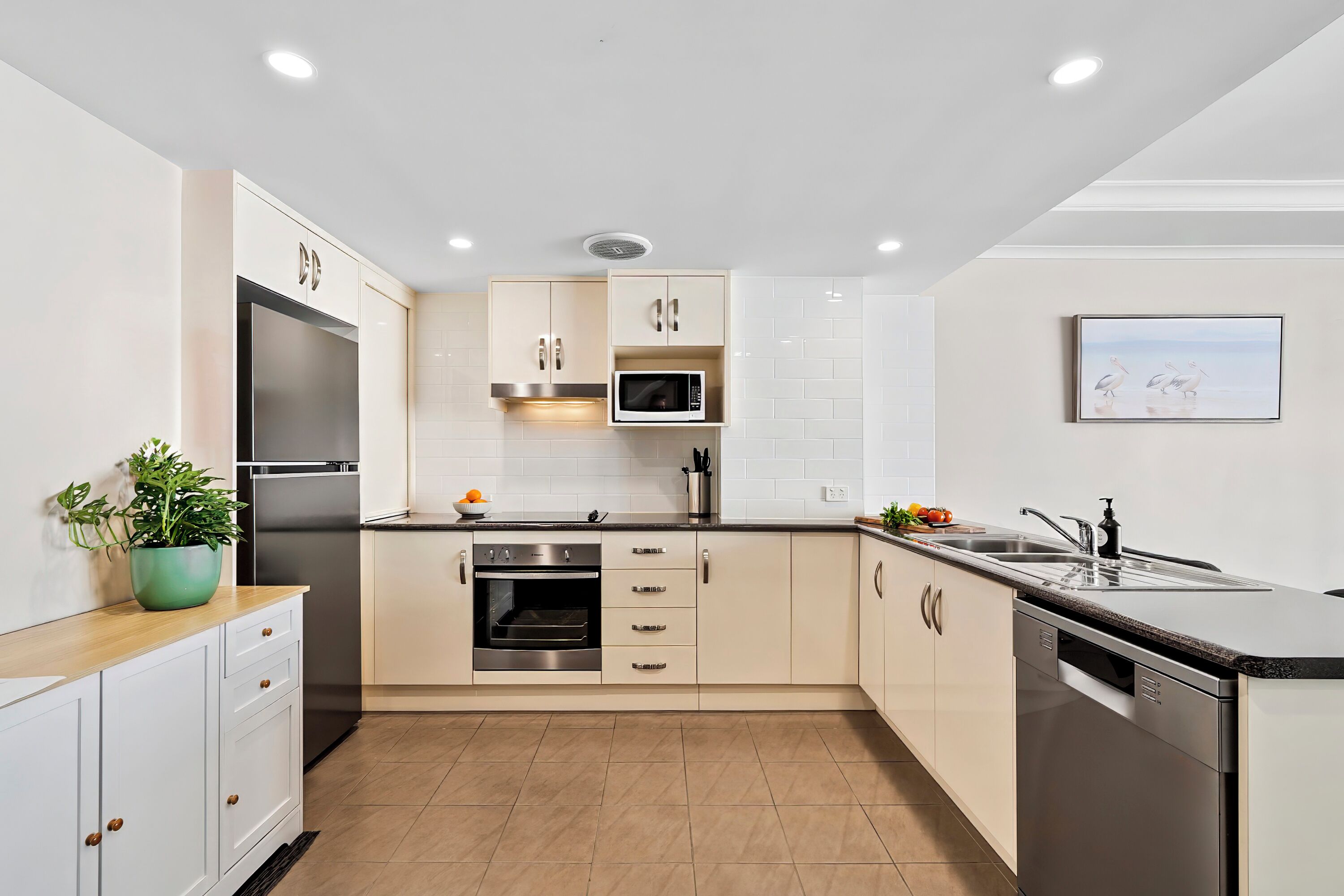 Cocina moderna con electrodomésticos de acero inoxidable, armarios blancos y salpicadero de azulejos.
