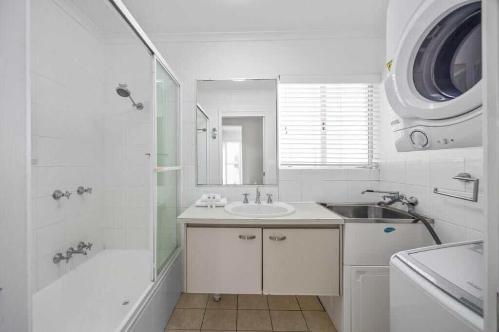Un baño moderno con bañera, ducha, lavabo y lavadora.