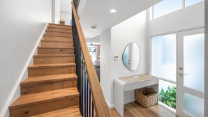 A wooden staircase leading to a landing with a white console table, a mirror, and a basket. - Skippers Cove Waterfront Resort (Noosaville)