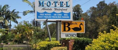 Letrero de motel que ofrece servicios como películas gratis, aire acondicionado, barbacoa y estacionamiento para barcos, remolques, camiones y autobuses.