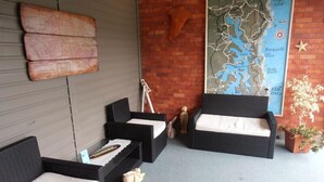 A cozy outdoor seating area with wicker furniture and a map on the wall. - Black Swan Waterfront Motel (Swansea)
