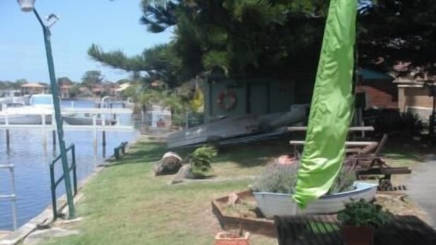 A waterfront patio with a table and chairs, a grassy area, and a railing overlooking the water. - Black Swan Waterfront Motel (Swansea)