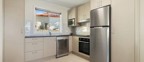 A kitchen with a dishwasher, oven, microwave, and refrigerator.