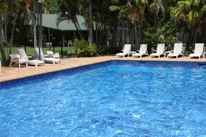 Una piscina al aire libre, sillones reclinables de piscina