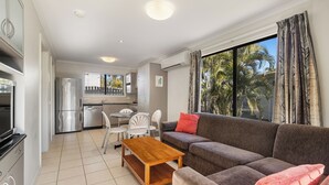 A modern living room with a sofa, a wooden coffee table, and a TV. - Brisbane Gateway Resort (Rochedale)