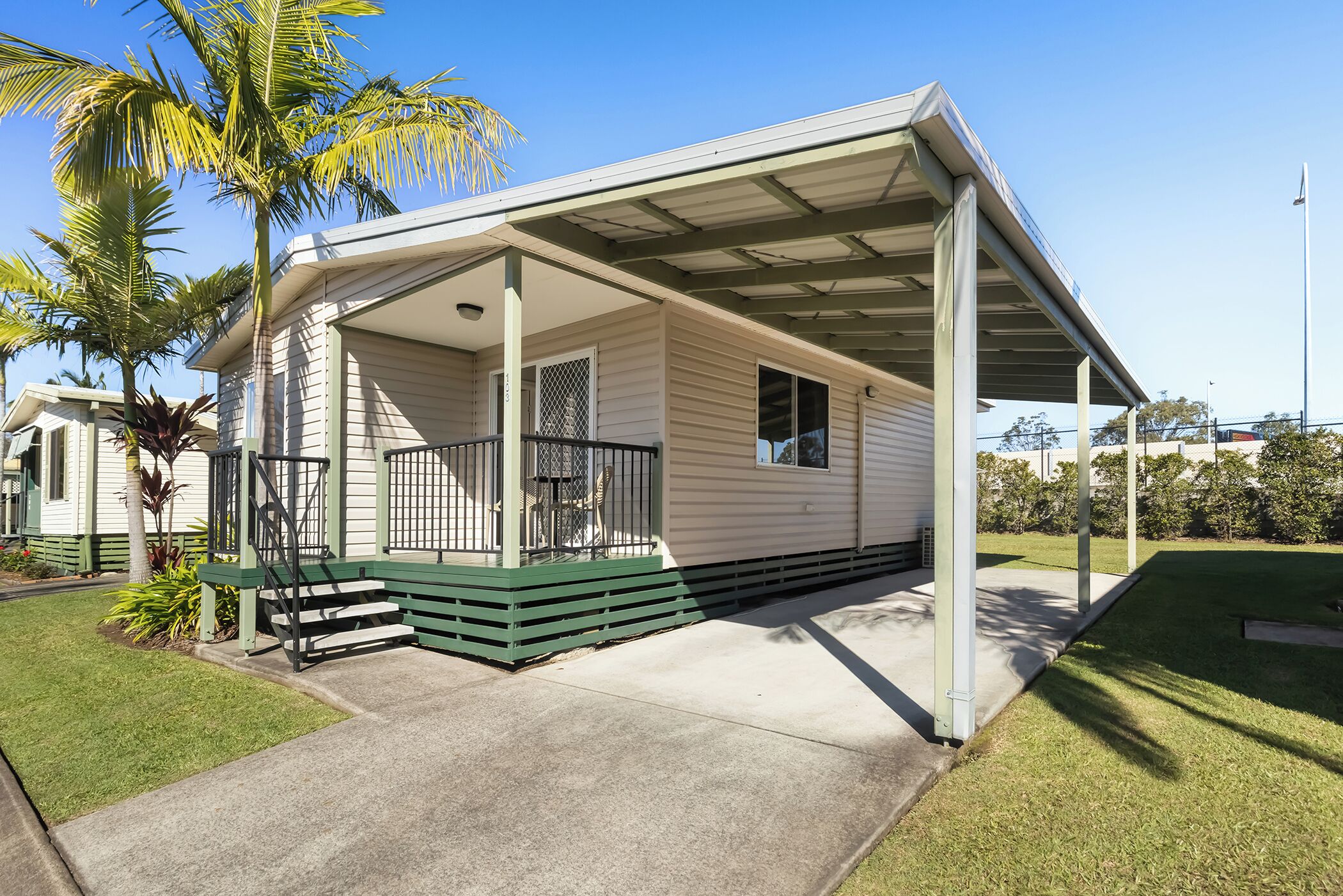A single-story house with a covered porch, a small front yard, and a palm tree.