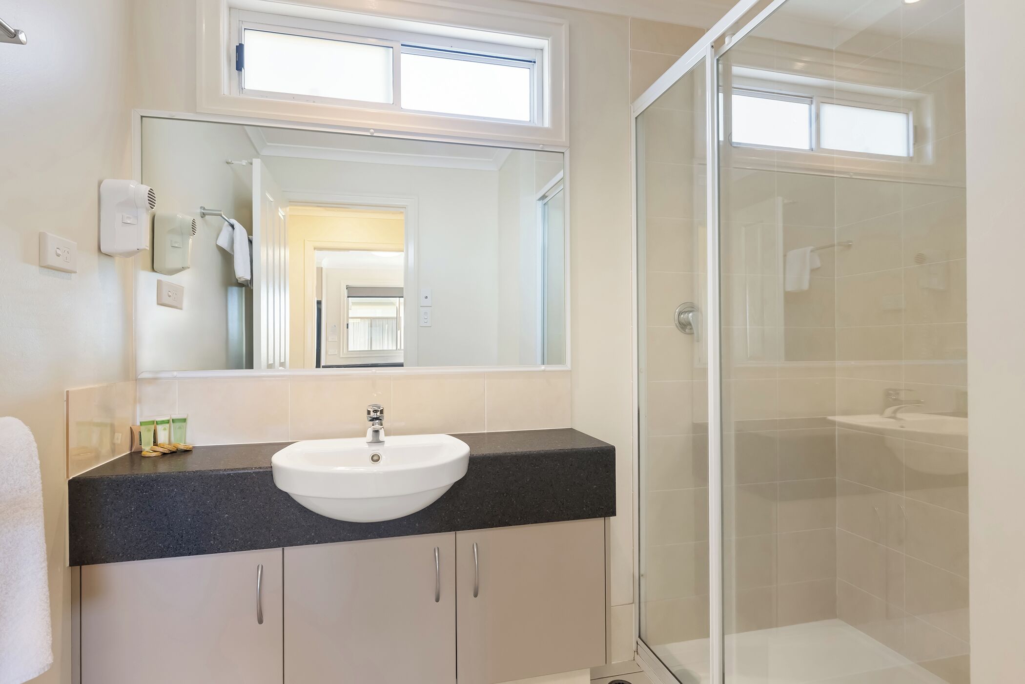 Un baño con lavabo, espejo y ducha.