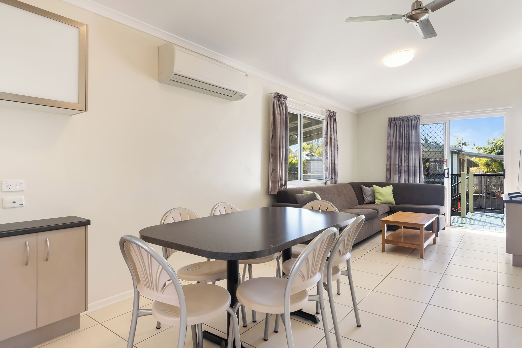 Un salon moderne comprenant un coin repas, un canapé et un ventilateur de plafond.