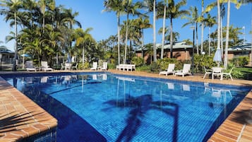 Una piscina al aire libre, sillones reclinables de piscina