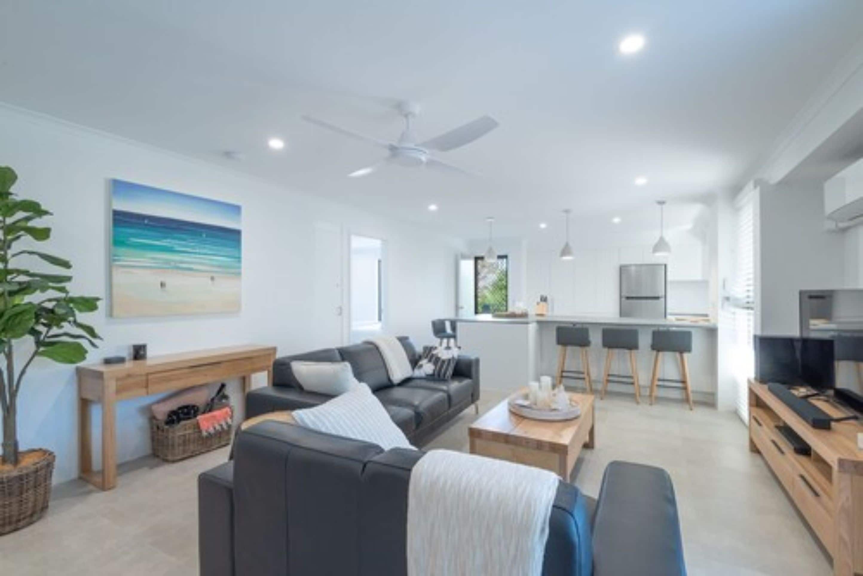 A modern living room with a sofa, coffee table, and a painting of a beach scene.