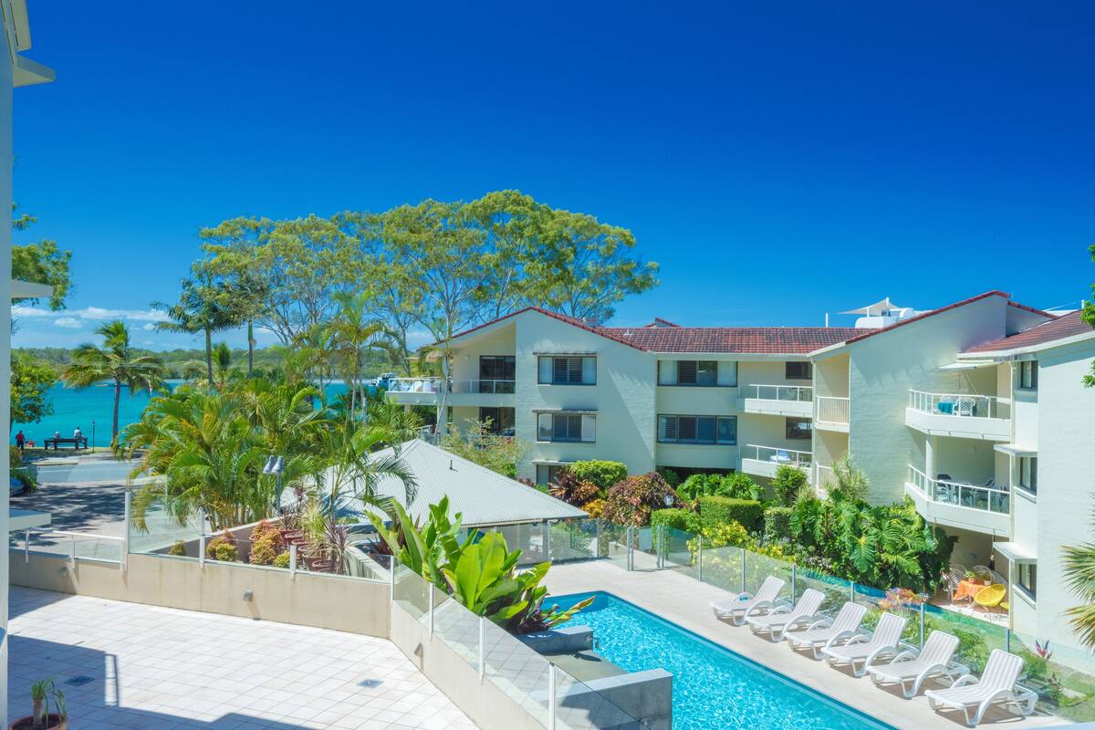 A hotel with a swimming pool, lounge chairs, and a view of the sea.